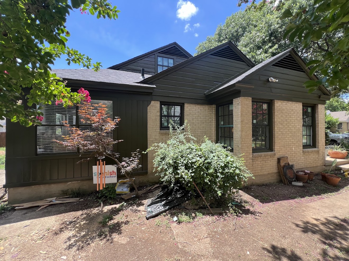 Exterior painting project by N&M Services: freshly painted dark siding and trim on a home with its original brick veneer.